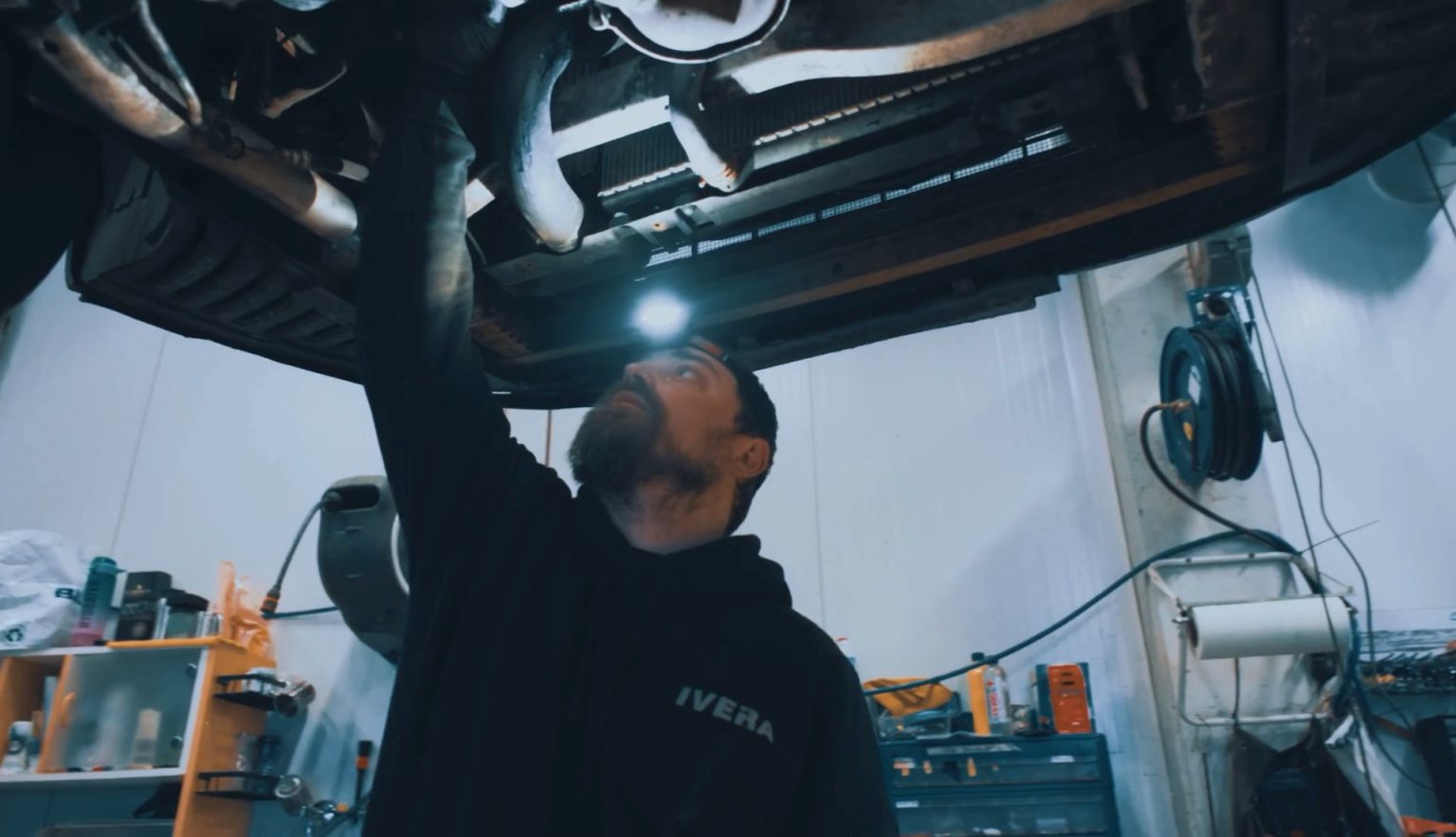 IVERA Autohuollon mekaanikko tarkastaa auton alustaa nosturilla Espoon Kiviruukissa