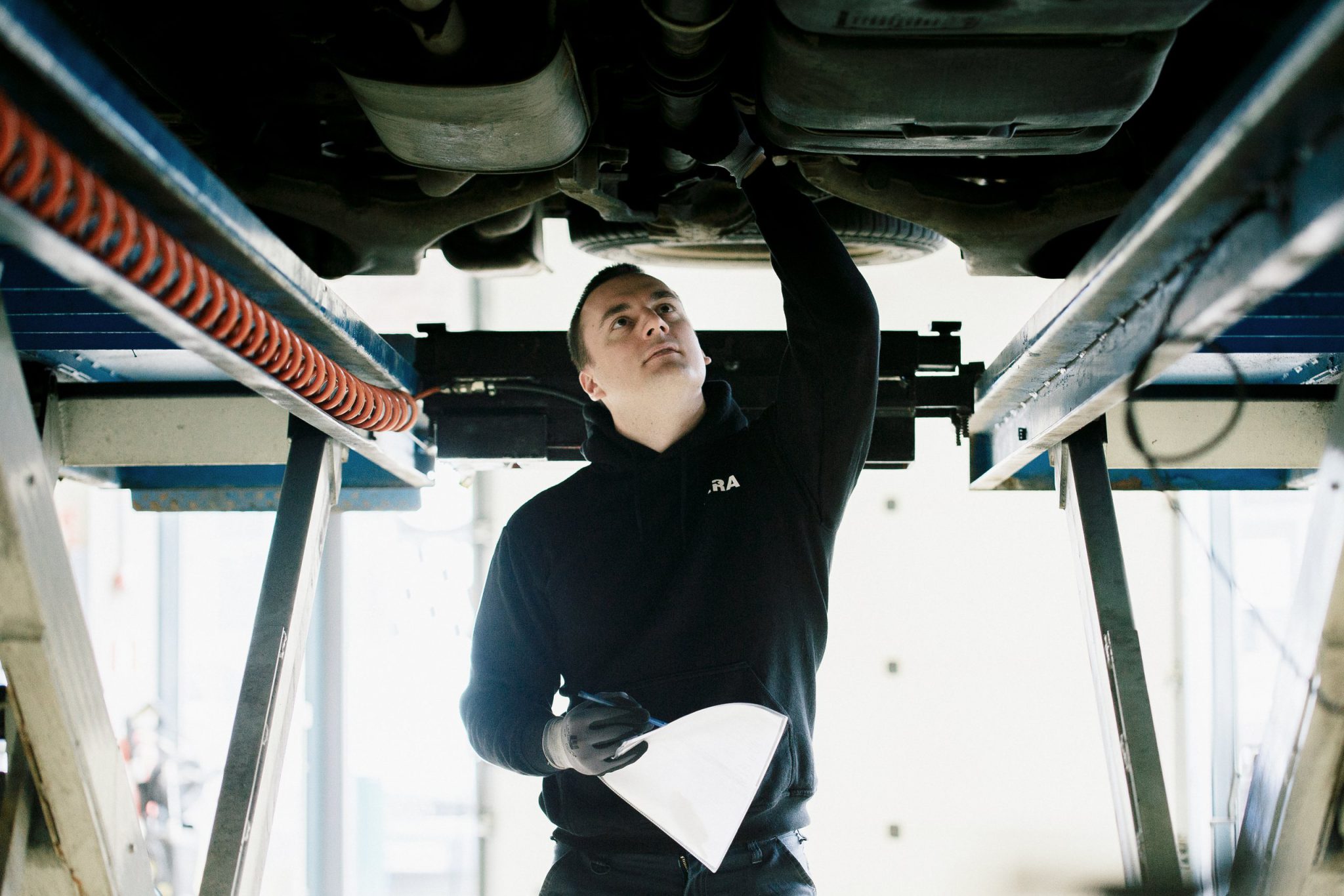 Mechanic inspecting the underside of a car on a lift